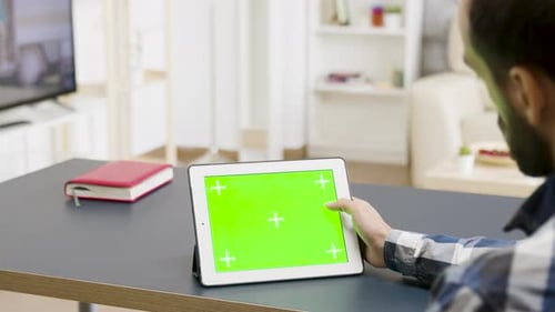 Man Scrolling and Touching a Green Screen of a Digital Tablet