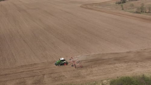 Aerial Top View of Tractor Cutting Furrows in Farm Field for Sowing Farm Tractor with Rotary Harrow