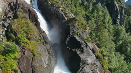 Breathtaking Waterfall Cascading Through Rocky Green Forest
