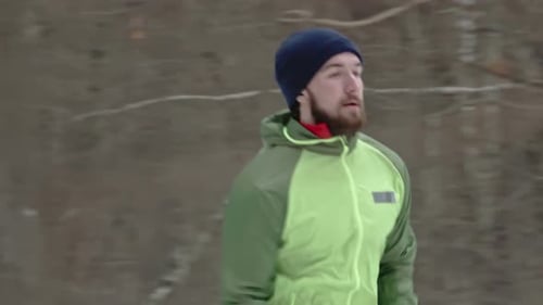 Man Running Through Snowy Forest in Winter