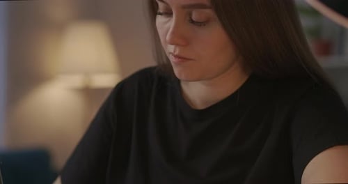 Woman Studying and Writing in Notebook at Desk