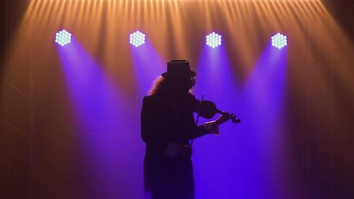 Silhouetted Musician Plays Violin on Dark Stage