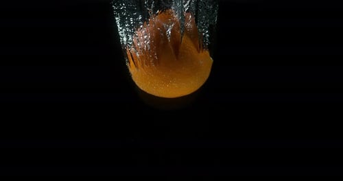 Orange, citrus sinensis, Fruit Falling into Water against Black Background, Slow Motion 4K