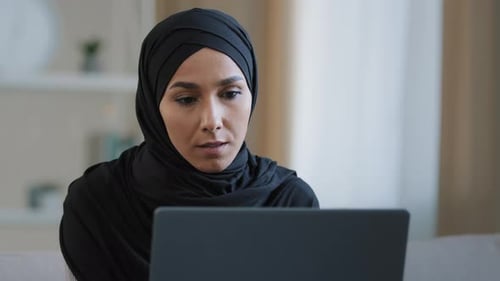 Woman with Headscarf Works on Laptop Indoors