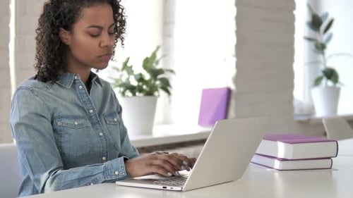 Pensive Creative African Girl Thinking and Working on Laptop