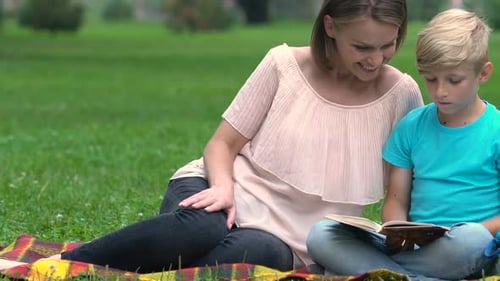 Woman and Child Reading Book Together Outdoors