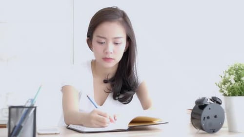 Young Adult Woman Writing in Notebook at Desk