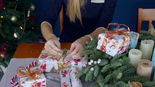 Woman Tying Gold Ribbon on Christmas Gift