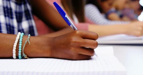 Student Hand Writing in Classroom Close-Up