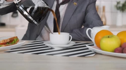 Man Pours Coffee at Breakfast Indoors