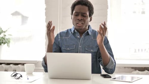 Frustrated Man Working on Laptop in Bright Office