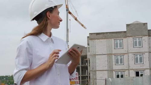 Mujer ingeniera civil usando una tableta en su lugar de trabajo en una obra de construcción