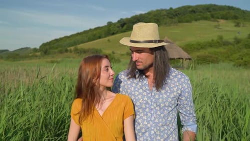 Couple Walking Arm in Arm Through Grassy Field