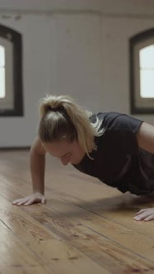 Medium Shot of Concentrated Young Woman Doing Pressups in Gym