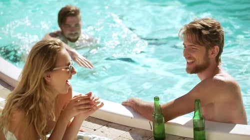 Two Caucasian Muscle Males in Pool Talking Laughing Smiling with Blonde Female Lying on Lounge