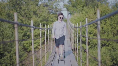 Guy Walks on Suspended Bridge in the Forest