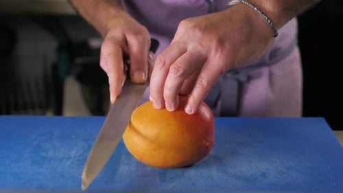 Man Cutting Mango in Kitchen with Sharp Knife
