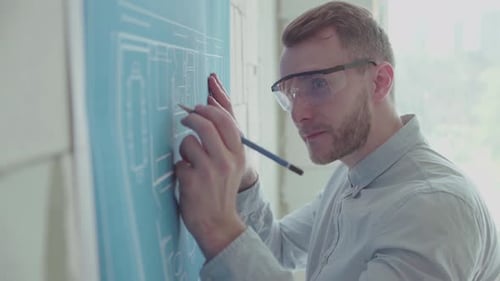 Young engineer-architect in a bright room works with blueprints