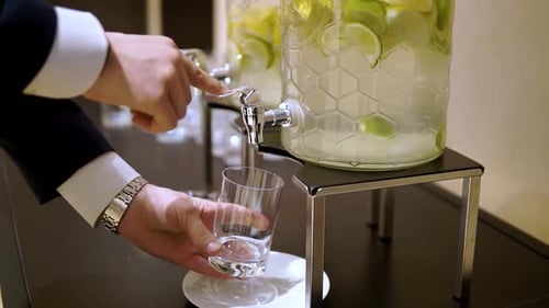 Man Fills Glass from Lemon and Lime Beverage Dispenser