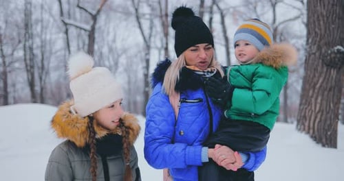 Beautiful Children Walk with a Young Mother in the Winter