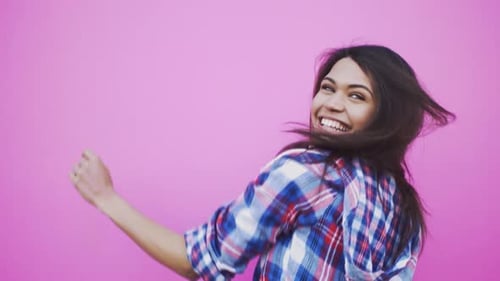 Woman Dancing and Smiling on Pink Background