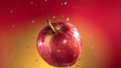 Fliegen von Red Apple auf rot-gelbem Hintergrund in Zeitlupe