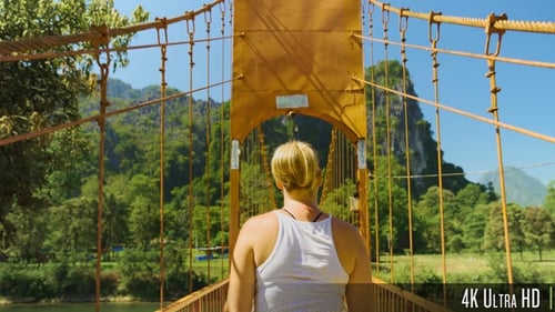 4K Woman Walking on Wood Suspension Bridge Walkway in the Mountains of Vang Vieng, Laos