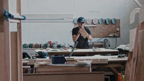 Man in a Carpentry Workshop Looking at the Grinded Wooden Piece