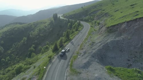 Drone Follows Blak SUV Towing Empty Trailer on Forest Mountain Road
