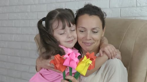 Child Embraces Mother with Paper Flowers