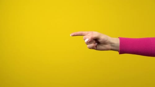 Die Hand zeigt den Zeigefinger zum leeren Raum. Studioaufnahmen auf einem isolierten gelben Hintergrund
