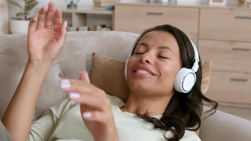 Woman Lying on Couch Enjoying Music