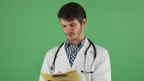 Young Male Doctor Writing on His Clipboard on Green Chromakey