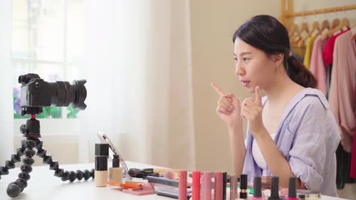 La bloguera de belleza presenta cosméticos de belleza sentada frente a la tableta para grabar un vídeo en la red social.