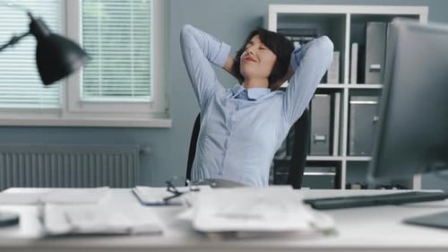Woman Relaxing at Desk with Arms Behind Head