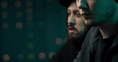 Um retrato em close de dois hackers analisando o código de malware que eles usarão