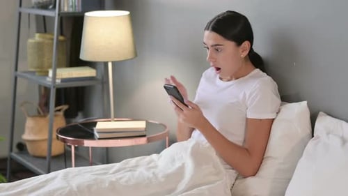 Failure Latin Woman Reacting to Loss on Smartphone in Bed