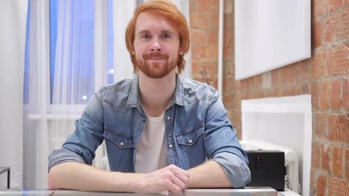 Portrait of Smiling Redhead Beard Man Looking at Camera in Office