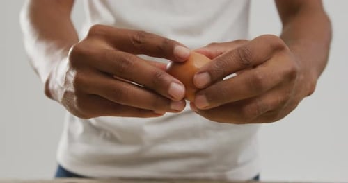 Video von Nahaufnahme eines biracial Mannes, der Ei auf weißem Hintergrund knackt