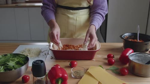 Person Assembling Delicious Lasagna in Bright Kitchen