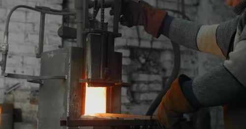 Metal Worker Using Forge Furnace in Industrial Setting