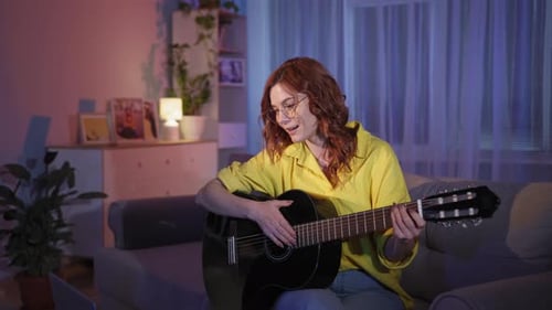 Young Woman Plays Guitar at Home