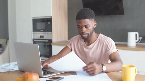 Young Adult Typing on Laptop at Kitchen Table