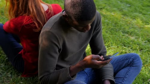 Young Adults Using Phones Back to Back Outside