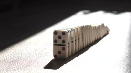 A Men Pushes a Domino and Starts a Chain Reaction on the Floor