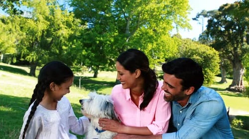 Family enjoying together with their pet dog in park
