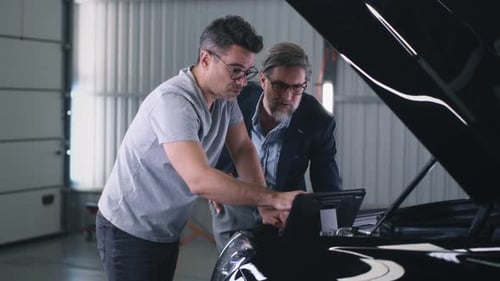 Mechanic Checking Car Engine Using Tablet
