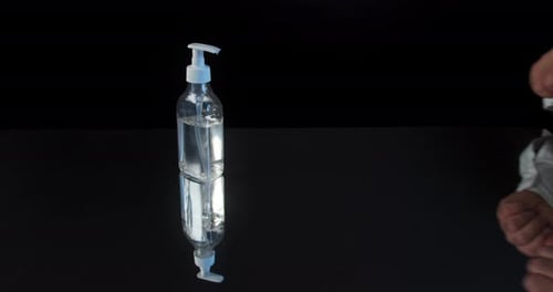 Man Push Dispenser und Flüssigseife zur Hand gedrückt, schwarzer Hintergrund.