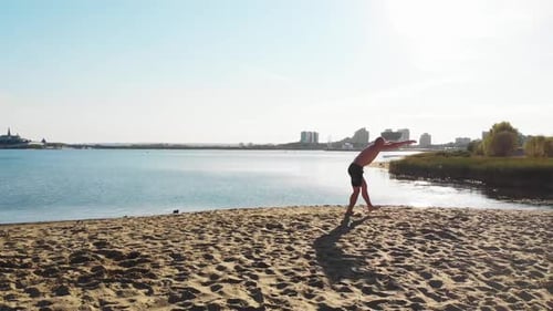 Young Man Running Up and Starts Doing a Series of Flips on the City Beach