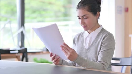 Woman Studying Documents in Bright Office Space